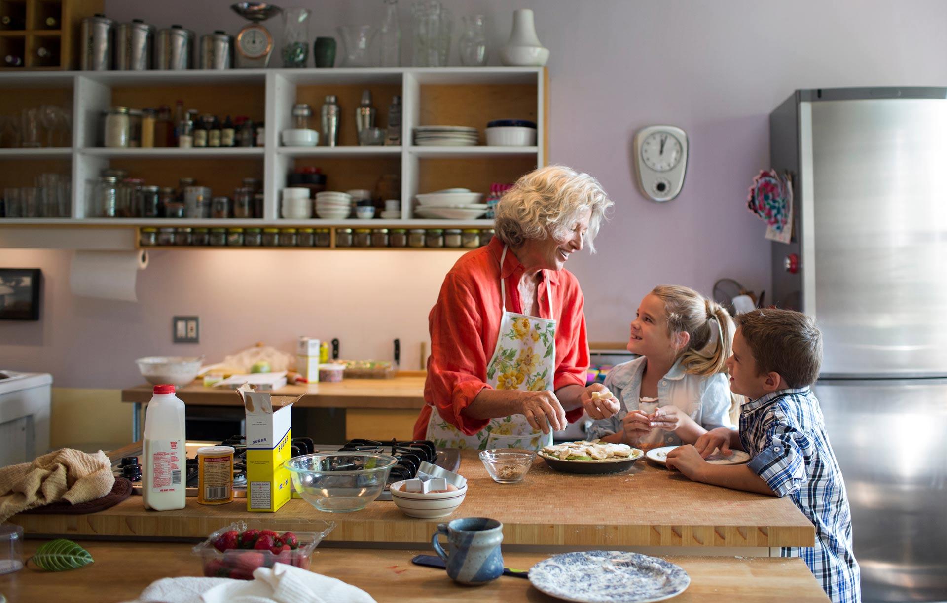Smiling Grandchildren Cooking With Grandmother in Kitchen